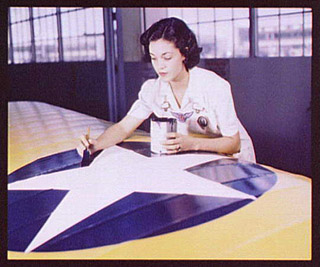 Woman painting American insignia on airplane wings, 1942. Woman painting American insignia on airplane wings, 1942.