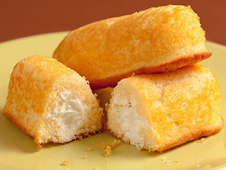 A plate of yellow sponge cakes filled with cream in the center. A plate of yellow sponge cakes filled with cream in the center.