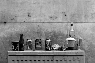 Black and white image of empty bottles on a metal lid with a concrete background. Black and white image of empty bottles on a metal lid with a concrete background.