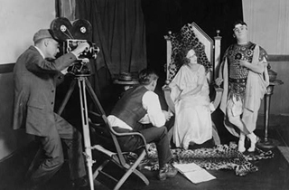 A photo of a cameraman, director and two actors on a set. A photo of a cameraman, director and two actors on a set.