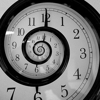 A black and white clock with a swirling face to indicate time travel. A black and white clock with a swirling face to indicate time travel.