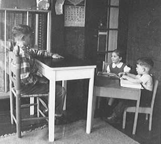 Black and white photograph of young children at desks. Black and white photograph of young children at desks.