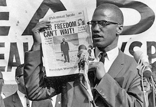 Malcolm X holds up a newspaper which reads, "Our Freedom Can't Wait" Malcolm X holds up a newspaper which reads, "Our Freedom Can't Wait"