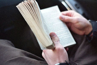 Focus on a man's hands holding a small book open. Focus on a man's hands holding a small book open.