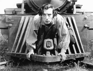 Photo of Buster Keaton crouched on the cowcatcher of a steam locomotive. Photo of Buster Keaton crouched on the cowcatcher of a steam locomotive.