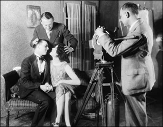 Two actors sitting on a couch with teacher directing a kissing scene. Two actors sitting on a couch with teacher directing a kissing scene.