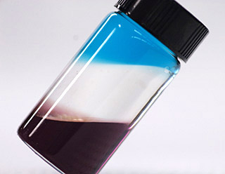 Photo of a vial containing three colored liquids in distinct layers. Photo of a vial containing three colored liquids in distinct layers.