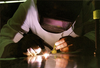 A photo of a tecnician welding, wearing a protective suit including a helmet and gloves. A photo of a tecnician welding, wearing a protective suit including a helmet and gloves.