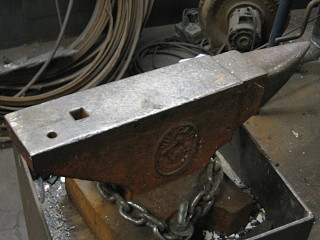 Photo of an anvil chained to a block stand. Photo of an anvil chained to a block stand.