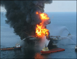 A large offshore drilling rig is up in flames. Several small ships are spraying it with water. A large offshore drilling rig is up in flames. Several small ships are spraying it with water.