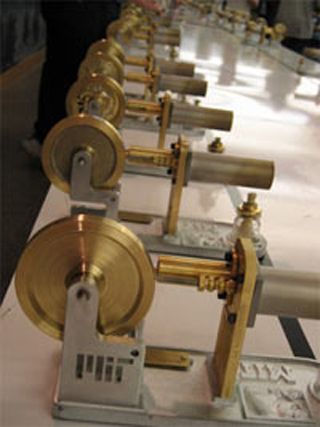 Photo of many, many Stirling engines lined up on a table. Photo of many, many Stirling engines lined up on a table.