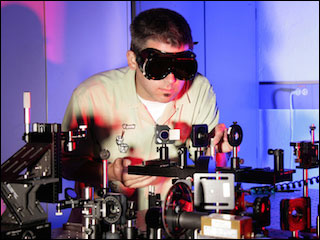 Researcher working with an optics table in laboratory. Researcher working with an optics table in laboratory.