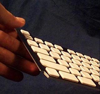 A photo of a hand holding a corner of a keyboard. A photo of a hand holding a corner of a keyboard.