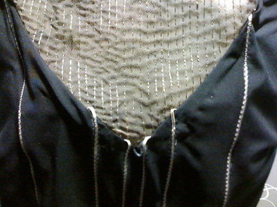 Photo of the front neckline portion of the dress, constructed of a light-colored (sheer?) material with thin wires embedded in it.