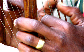 Closeup of two hands plucking kora strings. Closeup of two hands plucking kora strings.