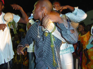 Several people playing small drums tucked under their arms. Several people playing small drums tucked under their arms.