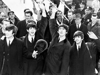 Four men on the tarmac at JFK airport waving to a crowd. Four men on the tarmac at JFK airport waving to a crowd.