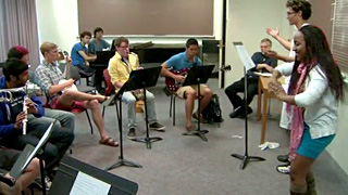 Photo of two students conducting in front of several other student instrumentalists. Photo of two students conducting in front of several other student instrumentalists.