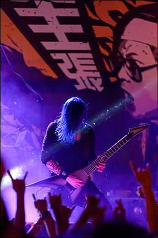 A man on stage playing the electric guitar in a concert. A man on stage playing the electric guitar in a concert.