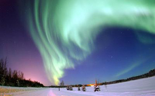 A green Aurora Borealis shimmers over snow-covered Alaskan fields. A green Aurora Borealis shimmers over snow-covered Alaskan fields.