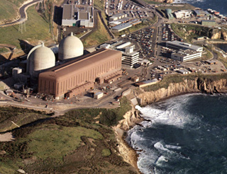 Photo of nuclear power plant on ocean shore, with two containment domes and a low rectangular building out front. Photo of nuclear power plant on ocean shore, with two containment domes and a low rectangular building out front.