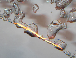 Flames and bubbles surround a thin wire submerged in water. Flames and bubbles surround a thin wire submerged in water.