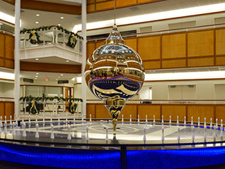 Photograph of a pendulum suspended from the ceiling over a circular base. Photograph of a pendulum suspended from the ceiling over a circular base.