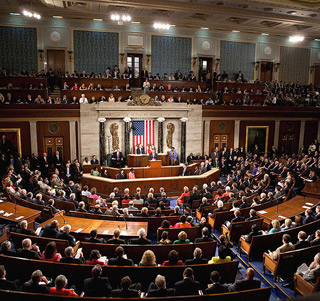 The members of Congress and the Senate are seated together in a half circle, listening to the President give an address. The members of Congress and the Senate are seated together in a half circle, listening to the President give an address.