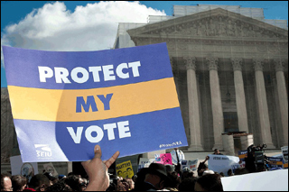 A hand holds a poster with the words "Protect My Vote" in front of the U.S. Supreme Court building. A hand holds a poster with the words "Protect My Vote" in front of the U.S. Supreme Court building.