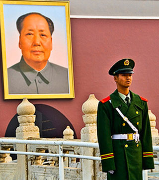 A guard in Beijing stands in front of the imperial palace where a large photo of Mao Zedong hangs. A guard in Beijing stands in front of the imperial palace where a large photo of Mao Zedong hangs.