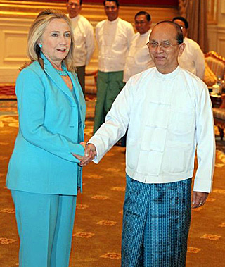 Hillary Clinton, in a teal pants suit, shakes the hand of Thein Sein, who is wearing a white buttoned shirt and teal lungi, a traditional Burmese garment, like a sarong. Hillary Clinton, in a teal pants suit, shakes the hand of Thein Sein, who is wearing a white buttoned shirt and teal lungi, a traditional Burmese garment, like a sarong.