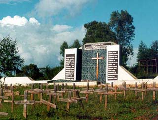 Image of a cemetery and memorial for the Rwandan genocide. A myriad simple crosses stand in front of a memorial. Image of a cemetery and memorial for the Rwandan genocide. A myriad simple crosses stand in front of a memorial.