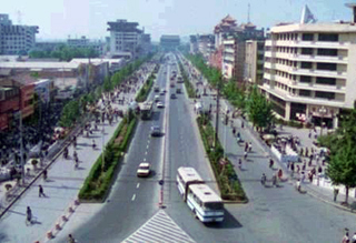 A photograph of a street in China. The street is lined with pedestrians. A photograph of a street in China. The street is lined with pedestrians.