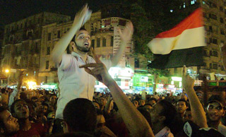 A bearded young man gestures wildly in the middle of a massive crowd. A bearded young man gestures wildly in the middle of a massive crowd.
