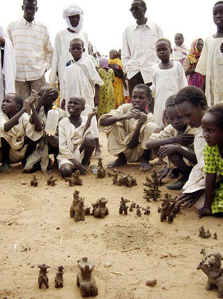 Children from the Sudan crouch on the ground playing with clay figures. Children from the Sudan crouch on the ground playing with clay figures.