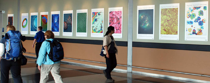 A woman walking and looking at scientific photographs on the wall of a hallway. A woman walking and looking at scientific photographs on the wall of a hallway.