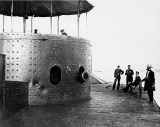 Several people standing next to gun turret of USS Monitor. Several people standing next to gun turret of USS Monitor.