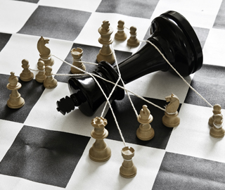 Several chess pieces hold down and oversized king with ropes. Several chess pieces hold down and oversized king with ropes.