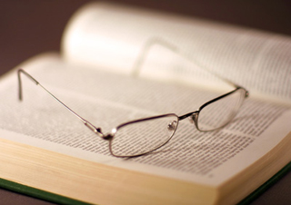 A pair of glasses sitting on an open book. A pair of glasses sitting on an open book.