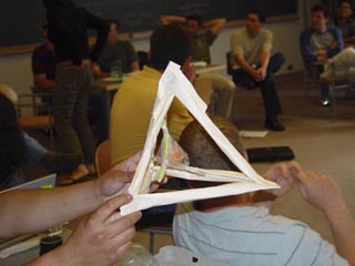 A photograph of a student-constructed egg protection device. The device consists of a paper pyramid with an egg suspended within. A photograph of a student-constructed egg protection device. The device consists of a paper pyramid with an egg suspended within.
