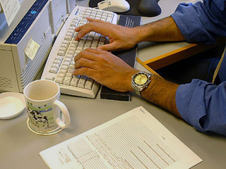 Photo of a man typing on a computer. Photo of a man typing on a computer.