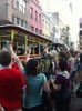 A trolley drives down a street crowded with people during a parade.