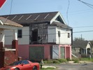 A dilapidated white and pink building sits on the corner in a neighborhood.