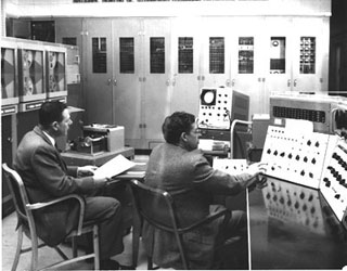A photograph of two engineers sitting before a massive computer. A photograph of two engineers sitting before a massive computer.