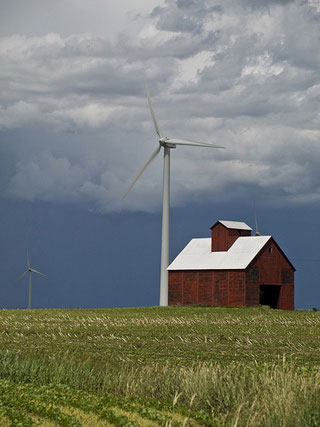 A wind turbine towers over a small red farmhouse. A wind turbine towers over a small red farmhouse.