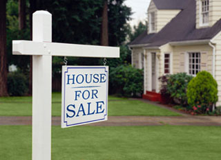A photograph of a home with a for sale sign in front of it. A photograph of a home with a for sale sign in front of it.