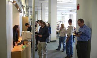 Library patrons standing before a desk. Library patrons standing before a desk.