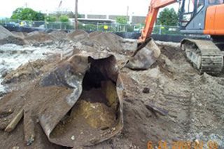 Image of a EPA cleanup site. A backhoe is extracting a metal tank from the ground. Image of a EPA cleanup site. A backhoe is extracting a metal tank from the ground.