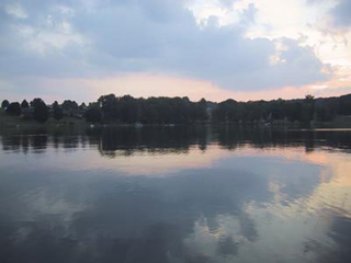 A photo of a calm lake with trees in the distance. A photo of a calm lake with trees in the distance.