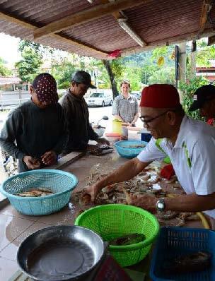 A group of men stand around a table cleaning fish.